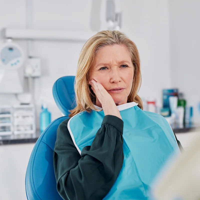 Patient holding her cheek in discomfort while sitting in a dental chair for emergency dental care at Riverfront Dental in Cambridge Ontario
