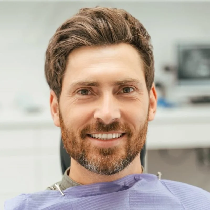 Smiling male patient sitting in a dental chair after teeth whitening treatment at Riverfront Dental in Cambridge Ontario